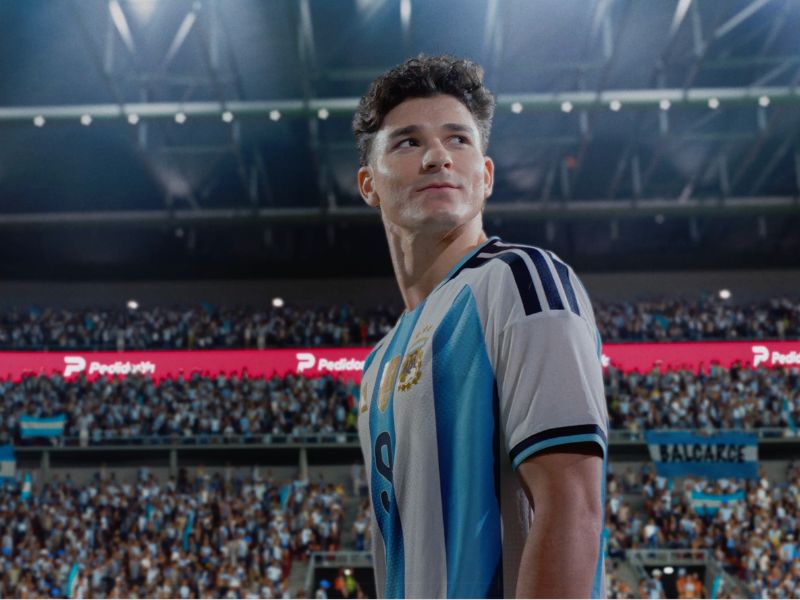 En uno de los dos comerciales, Julián Álvarez se prepara para patear un penal mientras a su alrededor se multiplican los pedidos: indicaciones cruzadas, contradictorias y cada vez más absurdas que terminan desbordando la escena. 